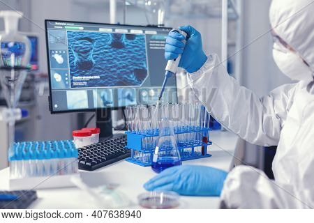 Laborant Dropping Sample In Test Tube Using Micropipette Dressed In Coverall. Chemist In Modern Labo