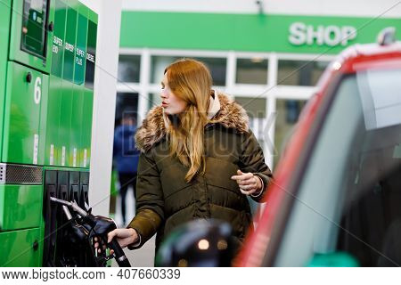 Young Caucasian Woman At Self-service Gas Station, Hold Fuel Nozzle And Refuel The Car With Petrol, 