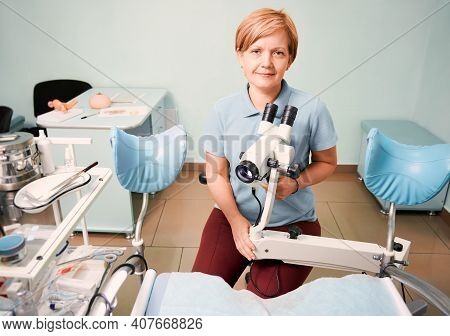 Portrait Of Woman Gynecologist Working In Gynecological Cabinet With Modern Equipment. Doctor Sittin