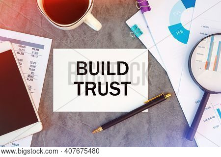 Build Trust Is Written In A Document On The Office Desk With Office Accessories, Coffee, Diagram And