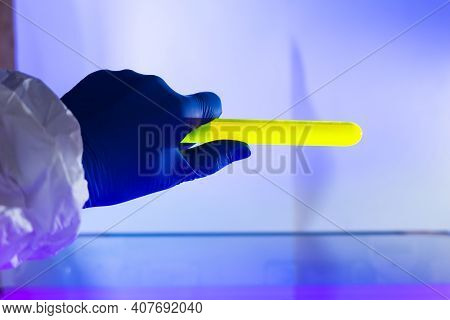 Fluorescein Glowing In Flask Under Ultraviolet Light. A Closeup Of Man Hand Holding Up A Vial  Fluor