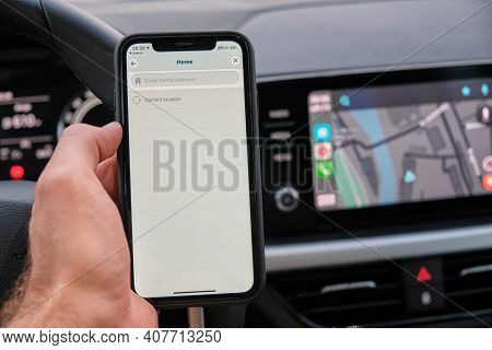 Waze On The Screen Of Smart Phone In Mans Hand On The Background Of Car Dashboard Screen With Applic
