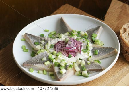 Herrings Fillets With Cream Sauce With Cucumbers, Red Onion And On Cutting Wooden Board