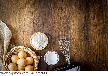 Baking Background. Flour In Woodencup, Eggs In Wicker Basket, Paper Cake Cup On Aluminium Cake Cup A