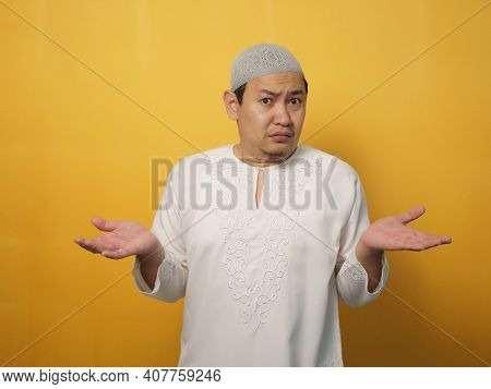Portrait Of Asian Muslim Man Shows Refusal Or Denial Gesture, Shoulder Shrug, I Don't Know Expressio
