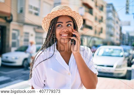 Young african american woman with braids smiling happy spaking on the phone outdoors on a sunny day of summer