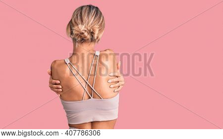 Beautiful caucasian woman wearing sportswear hugging oneself happy and positive from backwards. self love and self care 
