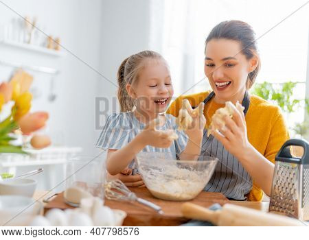 Happy loving family are preparing bakery together. Mother and child daughter girl are cooking cookies and having fun in the kitchen. Homemade food and little helper.     