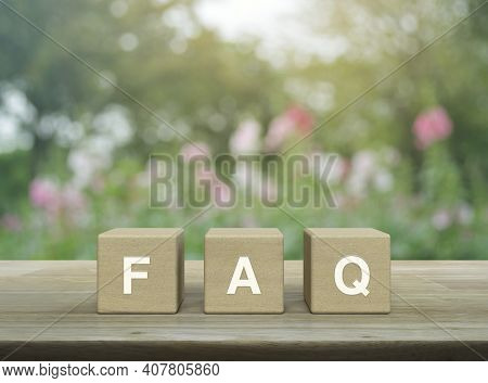 Faq Word On Block Cubes On Wooden Table Over Blur Pink Flower And Tree In Garden, Frequently Asked Q
