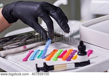 Close Up Of Doctor Hand In Sterile Glove Grabbing Blue Orthodontic Ligature Tie. Dentist Taking Rubb