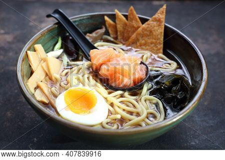 A Close-up Of A Traditional Japanese Ramen With Salmon, On A Black Stony Background.