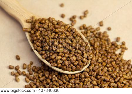Buckwheat Tea In A Wooden Spoon On A Brown Background. Buckwheat Tea Close-up Macro Photography. Sca