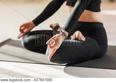 A Woman In Black Sportswear Practicing Yoga, Is Engaged In Meditation In The Lotus Position And Perf