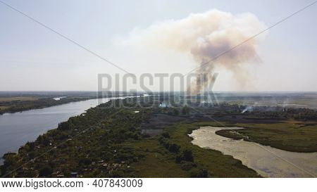 Drone Fly Over Waving River Of Blue Color Surrounded By Local Village With Various Buildings And Wet