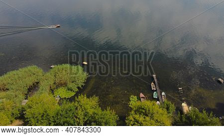 Drone Fly Over Waving River Of Blue Color Surrounded By Local Village With Various Buildings And Wet