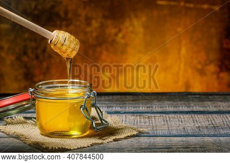 Honey Dripping From Honey Dripper Into Honey Jar