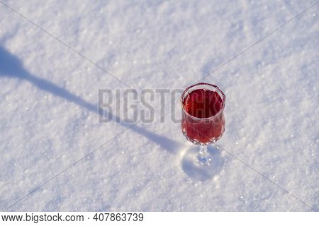 Homemade Tincture Of Red Cherry In A Wine Crystal Glass On A Snow And White Background , Ukraine, Cl