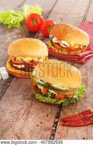 Delicious Veg And Non-veg Burgers Placed On A Wooden Board
