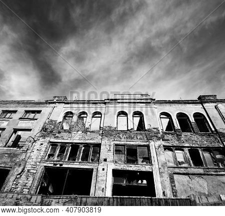 Black And White Facade Of Old Destroyed House With Broken Windows. Wide Angle View. High Contrast.