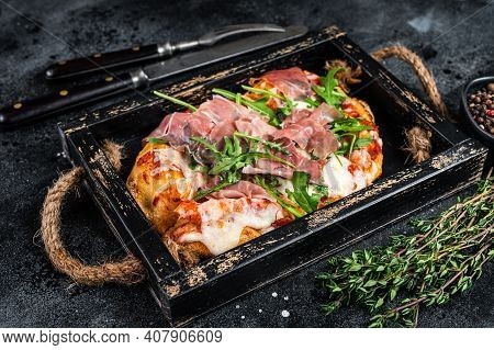 Italian Pizza With Prosciutto Parma Ham, Arugula Salad And Cheese In A Rustic Wooden Tray. Black Bac