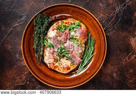 Pizza With Prosciutto Parma Ham, Arugula Salad And Parmesan Cheese In A Rustic Plate. Wooden Backgro
