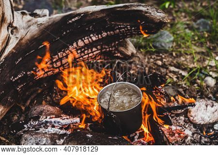 Kettle Stands On Fire. Cooking Food At Fire In Wild. Beautiful Big Log Burns In Bonfire Close-up. Su