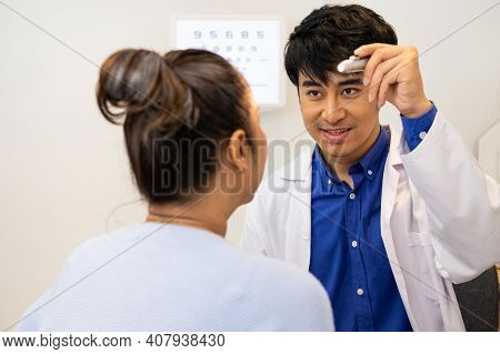 Selective Focus At Optometrist Face. While Doctor Using Penlight And Subjective Refraction To  Exami