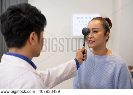 Selective Focus At Optometrist Face. While Doctor Using Penlight And Subjective Refraction To  Exami
