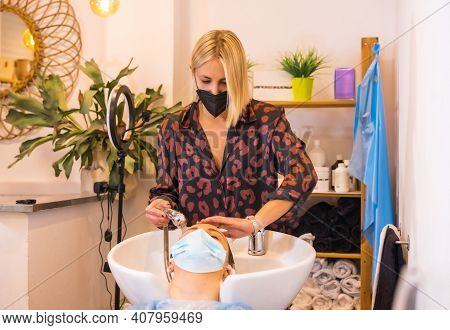 Hairdresser With Face Protection Mask Washing The Client\'s Hair With Soap And Water. Opening With S