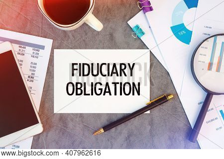 Fiduciary Obligation Is Written In A Document On The Office Desk With Office Accessories, Coffee, Di