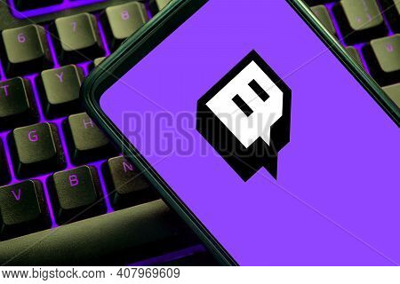 Twitch Icon On A Cellphone Screen On A Purple Illuminated Gaming Keyboard. Video Game Streaming Site