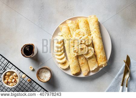Rolled Pancakes, Crepes Served With Banana, Nuts, Coconut And Date Syrup. Delicious Homemade Breakfa