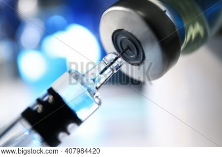 Filling Syringe With Vaccine From Vial On Blurred Background, Closeup