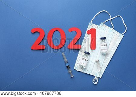 Flat Lay Composition With Coronavirus Vaccine And Number 2021 On Blue Background