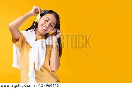 Happy Young Asian Woman Listening Music In Headphones And Dancing Over Yellow Background Charming Gi