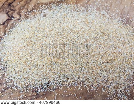Dried Garlic Granules On Brown Olive Wood