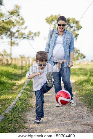 Happy Son Playing With Soccer Ball, And His Pregnacy Mother Looking