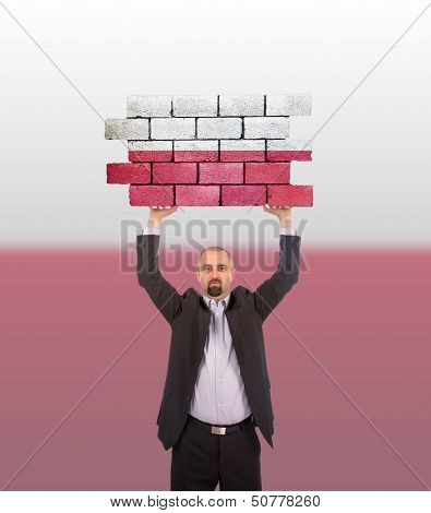 Businessman Holding A Large Piece Of A Brick Wall