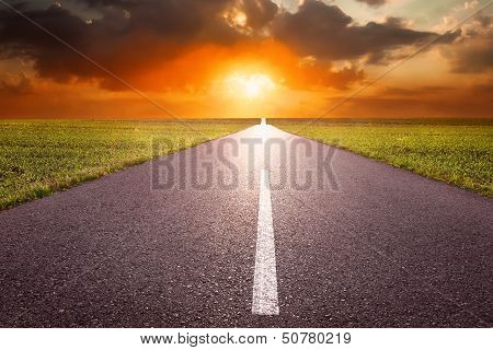 Driving On An Empty Road Towards The Setting Sun