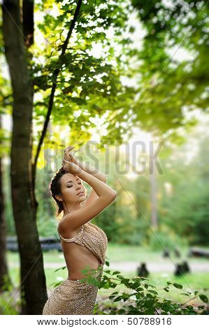 Beautiful Young Woman In Dress In Garden On Sunset
