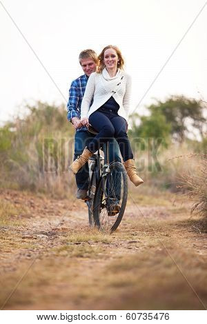 Happy Couple Riding Old Bicylce On Dirt Road