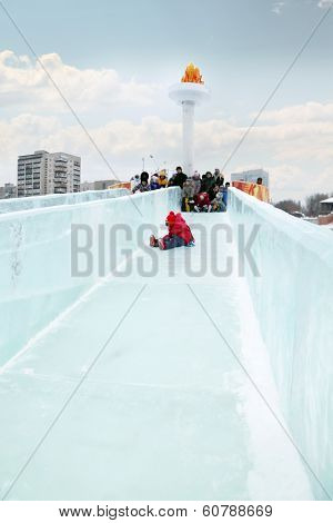 Little Girl In Red Rolls To Ice Slide In Ice Town In Perm, Russia, Created In Honor Of Winter Olympi