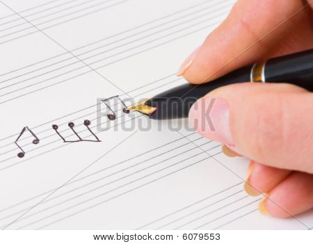 Main avec le stylo et la feuille de musique