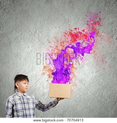 Young boy splashing colorful paint from carton box