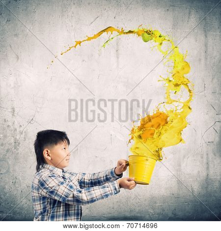 Young boy splashing colorful paint from bucket