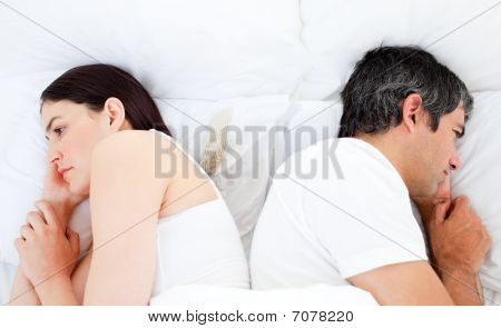 Järkyttynyt pari nukkuu sängyssä erikseen