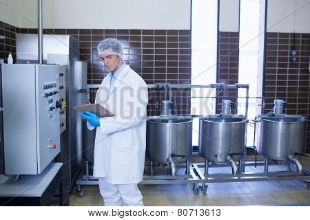 Focused biologist with safety gloves holding clipboard in the factory