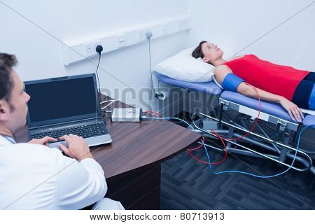 Doctor checking blood pressure of woman at medical office