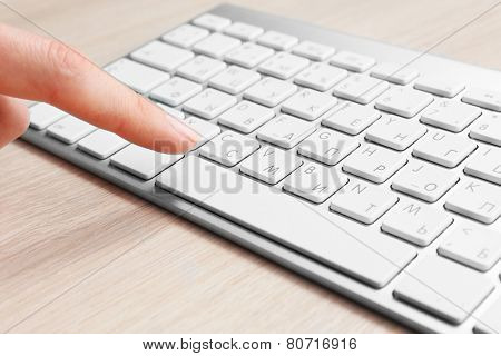 Female hand with keyboard on wooden desktop background