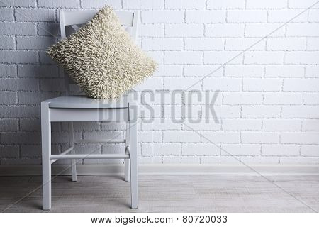Modern interior with chair and pillow on white brick wall background